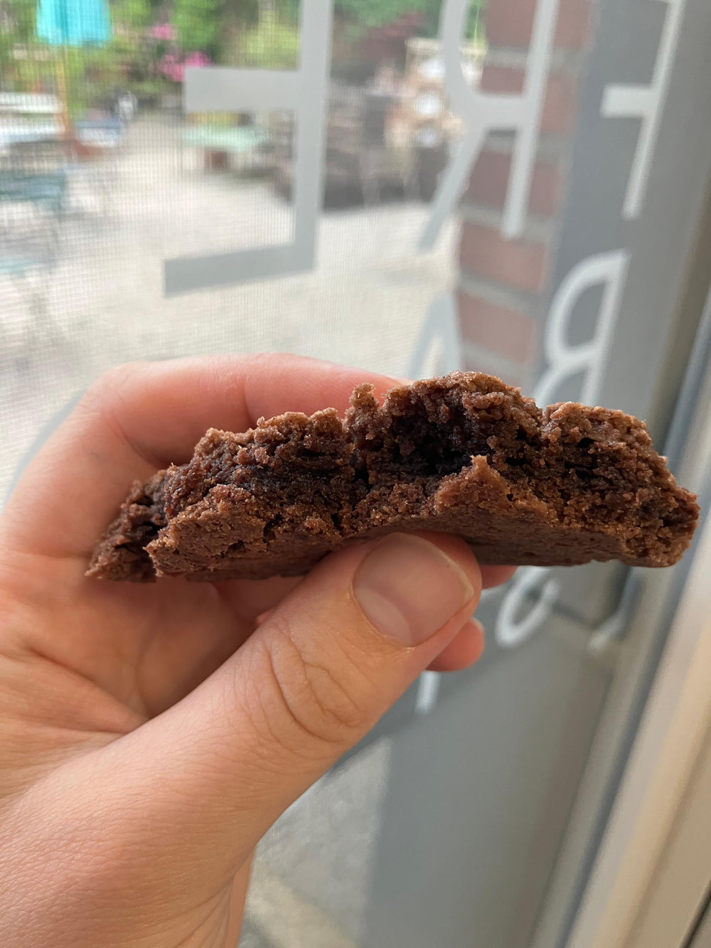 Ein aufgeschnittener glutenfreier Schokocookie im Vordergrund. fotografiert vor der tür der glutenfreien Backstube